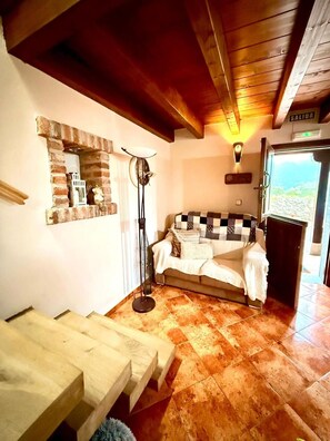 Una habitación acogedora con un sofá estampado en cuadros, una mesita, una chimenea de ladrillo y una vista por una puerta.