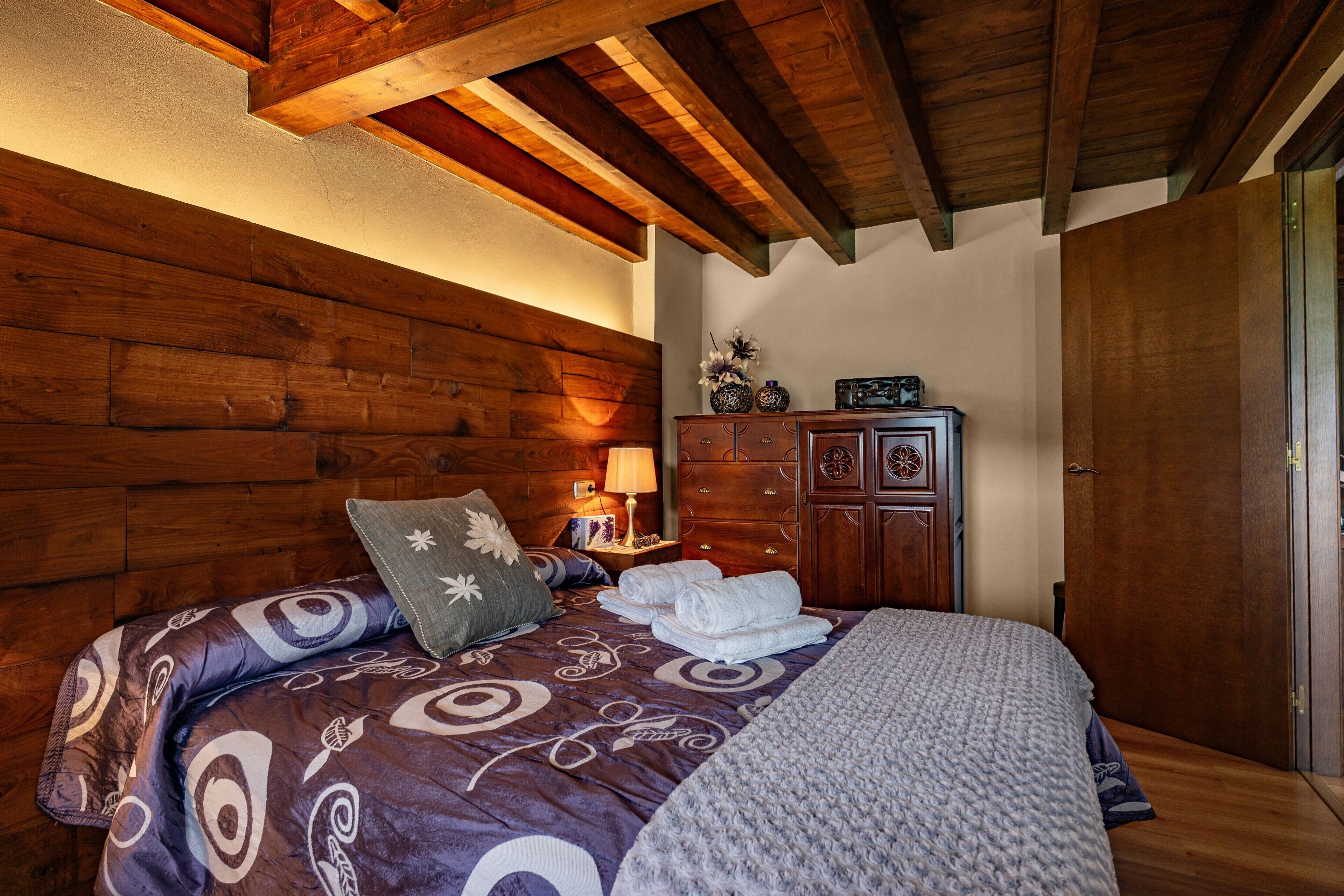 Una habitación con paneles de madera, una cama, un aparador y una puerta.