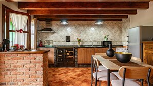 A kitchen with a brick island, wooden cabinets, a tiled backsplash, and a dining area with a table and chairs.