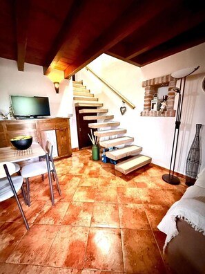 Comedor con televisión, escalera y ventilador.