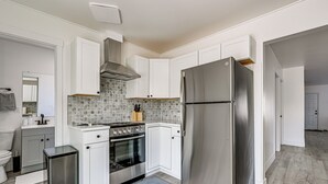 A modern kitchen with white cabinets, a stainless steel refrigerator, a built-in oven, and a tiled backsplash. - Updated + Modern Craftsman Bungalow in Renton! (Renton)