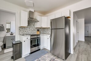 A modern kitchen with white cabinets, a stainless steel refrigerator, a built-in oven, and a tiled backsplash.