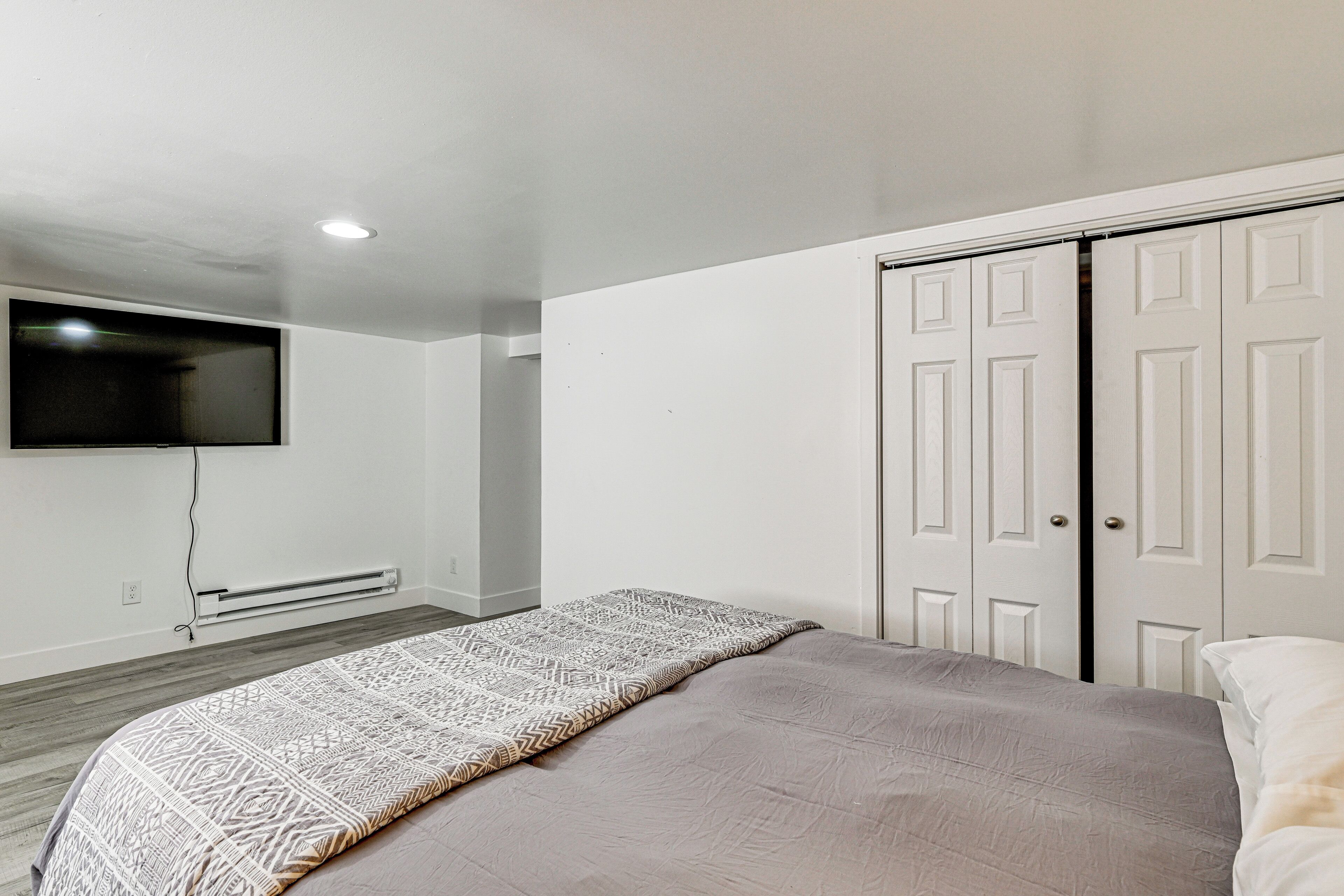 Une chambre à coucher comprenant un lit, un téléviseur fixé au mur, un radiateur et une armoire.