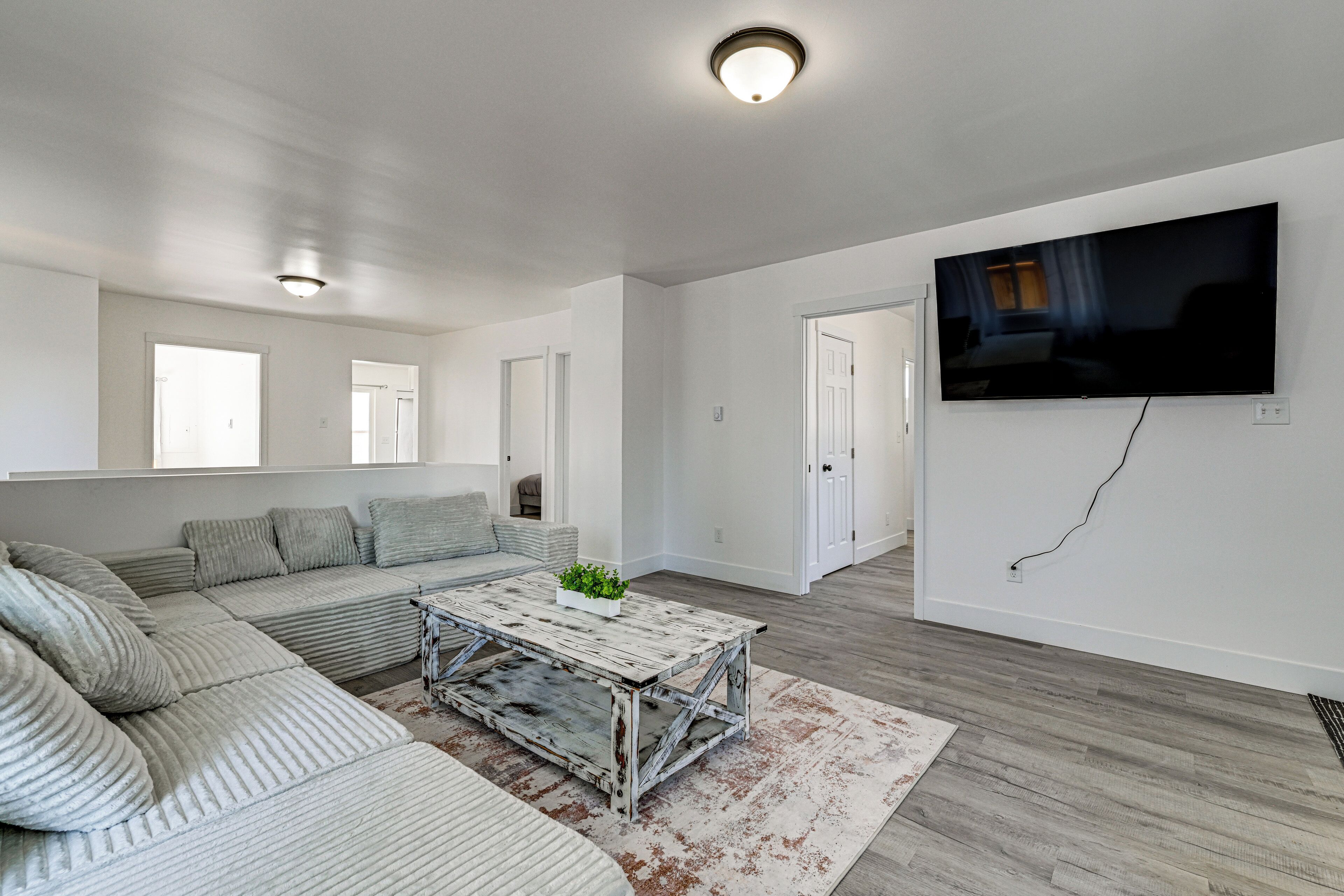 A modern living room with a sectional sofa, a rustic coffee table, a flat-screen TV, and a large window.