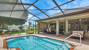 Una piscina cubierta con zona de patio, sillas y vistas al exterior.