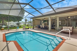 A covered swimming pool with a patio area, chairs, and a view of the outdoors. - Weeki Wachee Retreat: Heated Pool and Fenced Yard (Spring Hill)