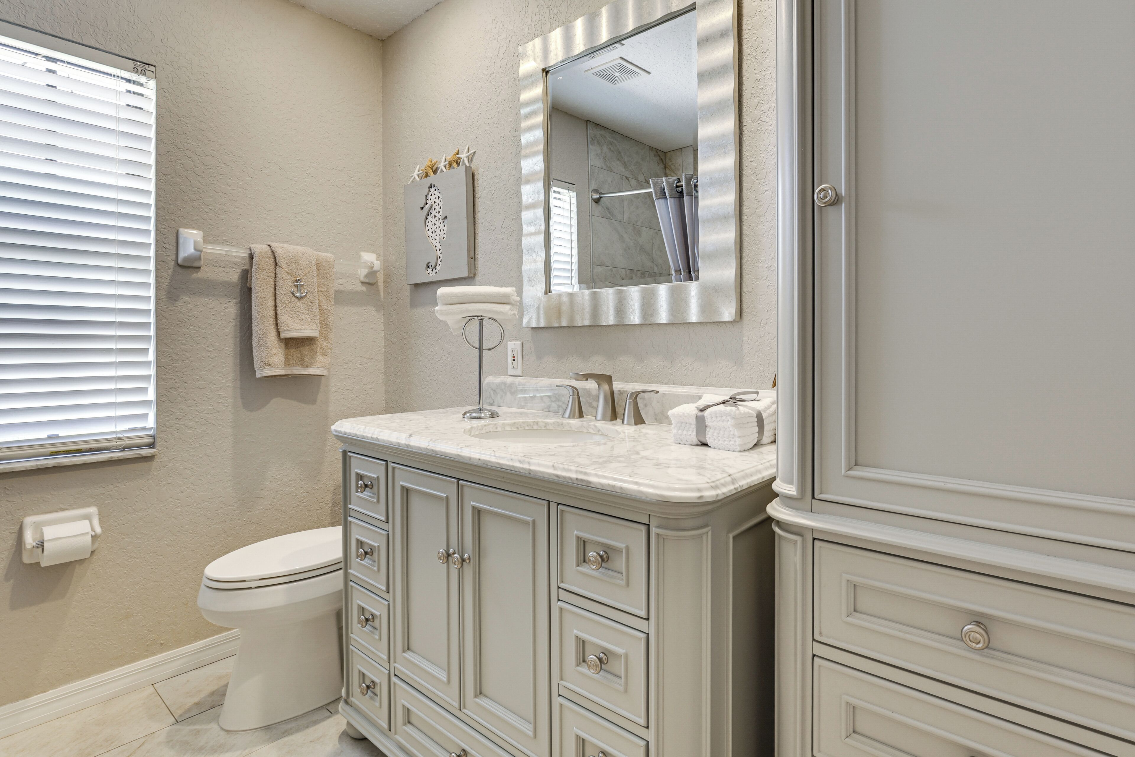 Une salle de bain comprenant des toilettes, un meuble-lavabo avec des tiroirs, un miroir et une douche.