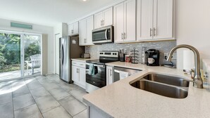 A modern kitchen with white cabinets, a stainless steel sink, a microwave, and a dishwasher. - Walk to Ocean! Fernandina Beach 3-unit Getaway (Fernandina Beach)