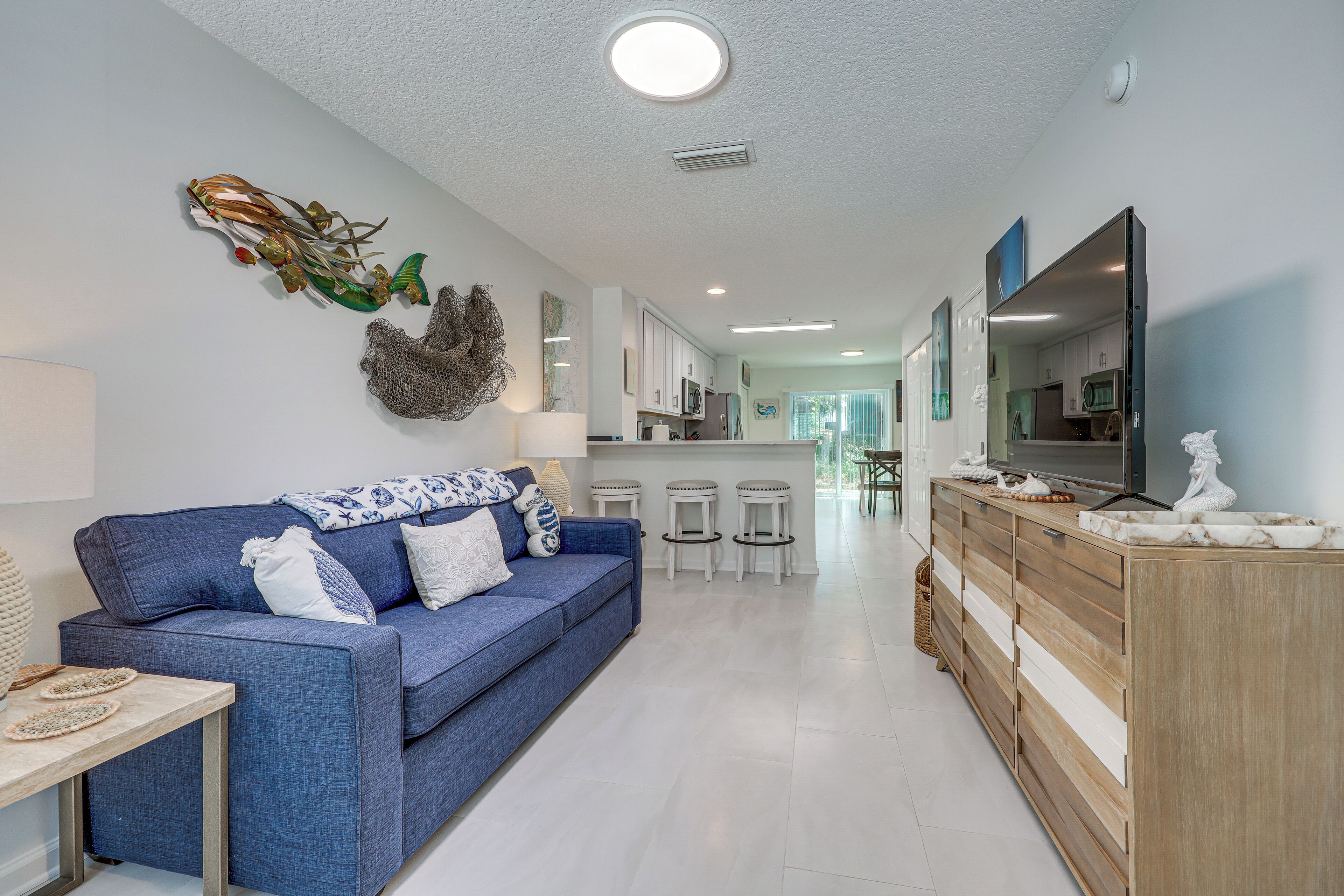 A modern living room with a blue sofa, a wooden cabinet, and a flat-screen TV.