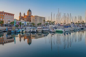 Un port de plaisance avec des bateaux amarrés, une église imposante surmontée de coupoles et un bâtiment doté de balcons.