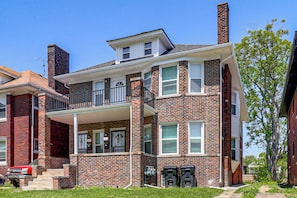 A two-story brick house with a front porch, a chimney, and a visible garage door. - Under 1 Mi to Med Center & Midtown: Detroit Apt (Detroit)