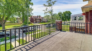A residential balcony with a metal railing, a concrete floor, and a view of a suburban neighborhood with houses and parked cars. - Under 1 Mi to Med Center & Midtown: Detroit Apt (Detroit)