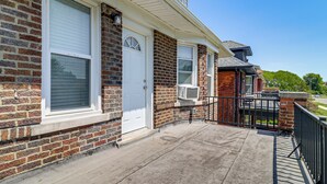 A two-story brick house with a white door, large windows, and a concrete porch. - Under 1 Mi to Med Center & Midtown: Detroit Apt (Detroit)