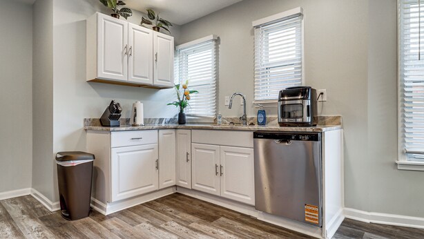 A modern kitchen with white cabinetry, a dishwasher, a coffee maker, and a trash can. - Under 1 Mi to Med Center & Midtown: Detroit Apt (Detroit)