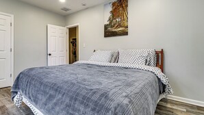 A bedroom with a large bed, a door, and a painting on the wall. - Under 1 Mi to Med Center & Midtown: Detroit Apt (Detroit)