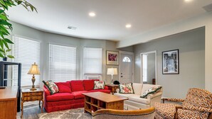 A living room with a red sofa, a patterned armchair, a wooden coffee table, and a lamp. - Under 1 Mi to Med Center & Midtown: Detroit Apt (Detroit)
