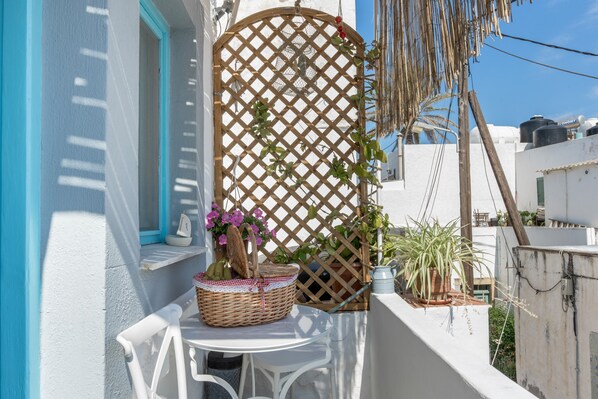 A balcony with a white table, wicker basket, potted plants, and a wooden lattice.