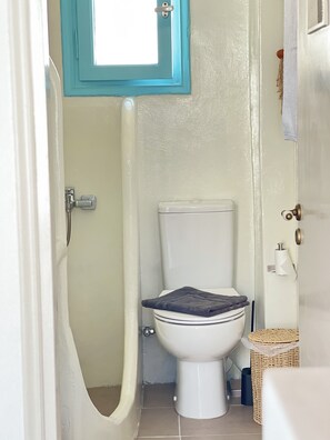 Ein Badezimmer mit Toilette, Dusche, Handtuchhalter und einem kleinen Korb.