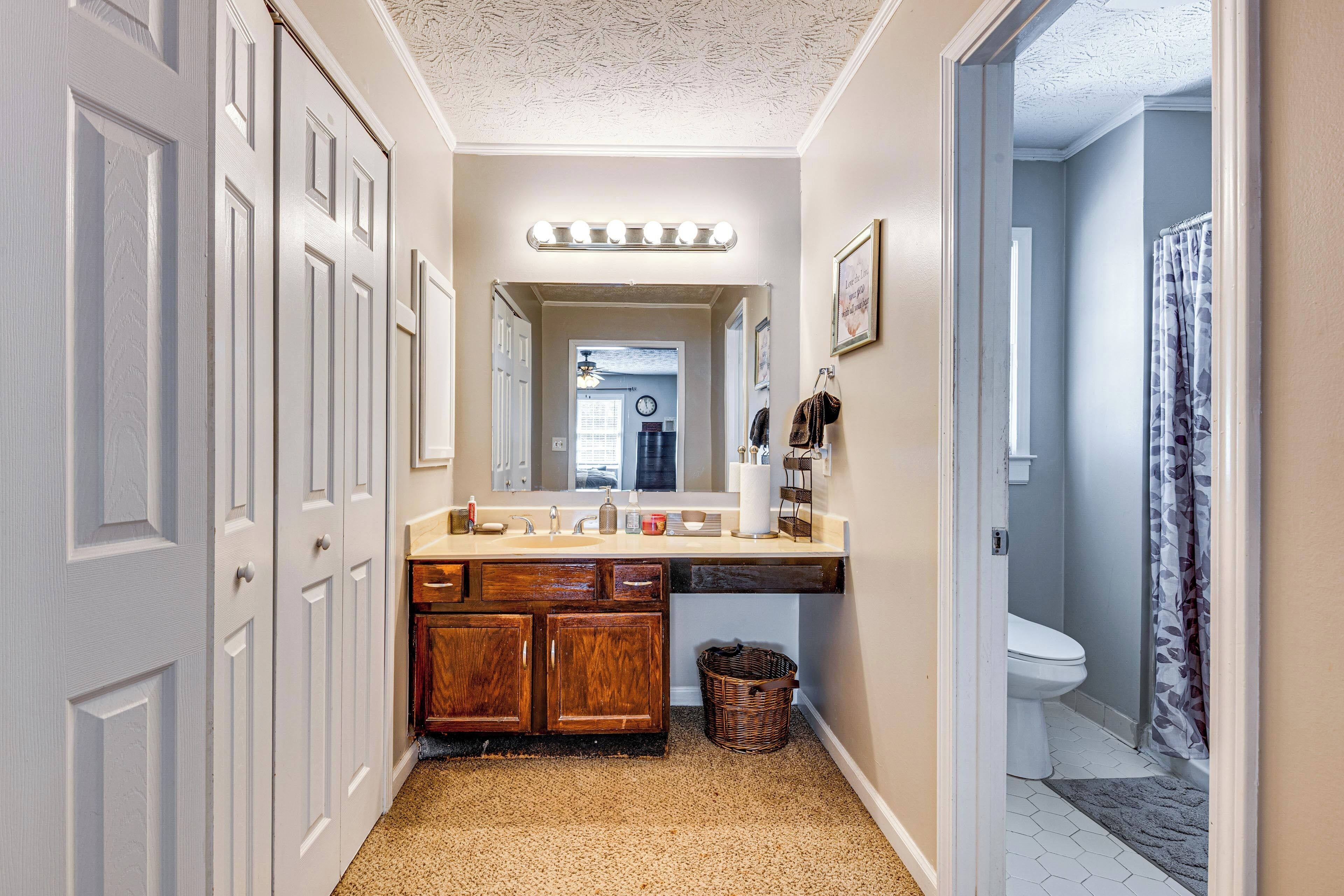 A hallway with a bathroom, a vanity with a mirror, and a shower curtain.