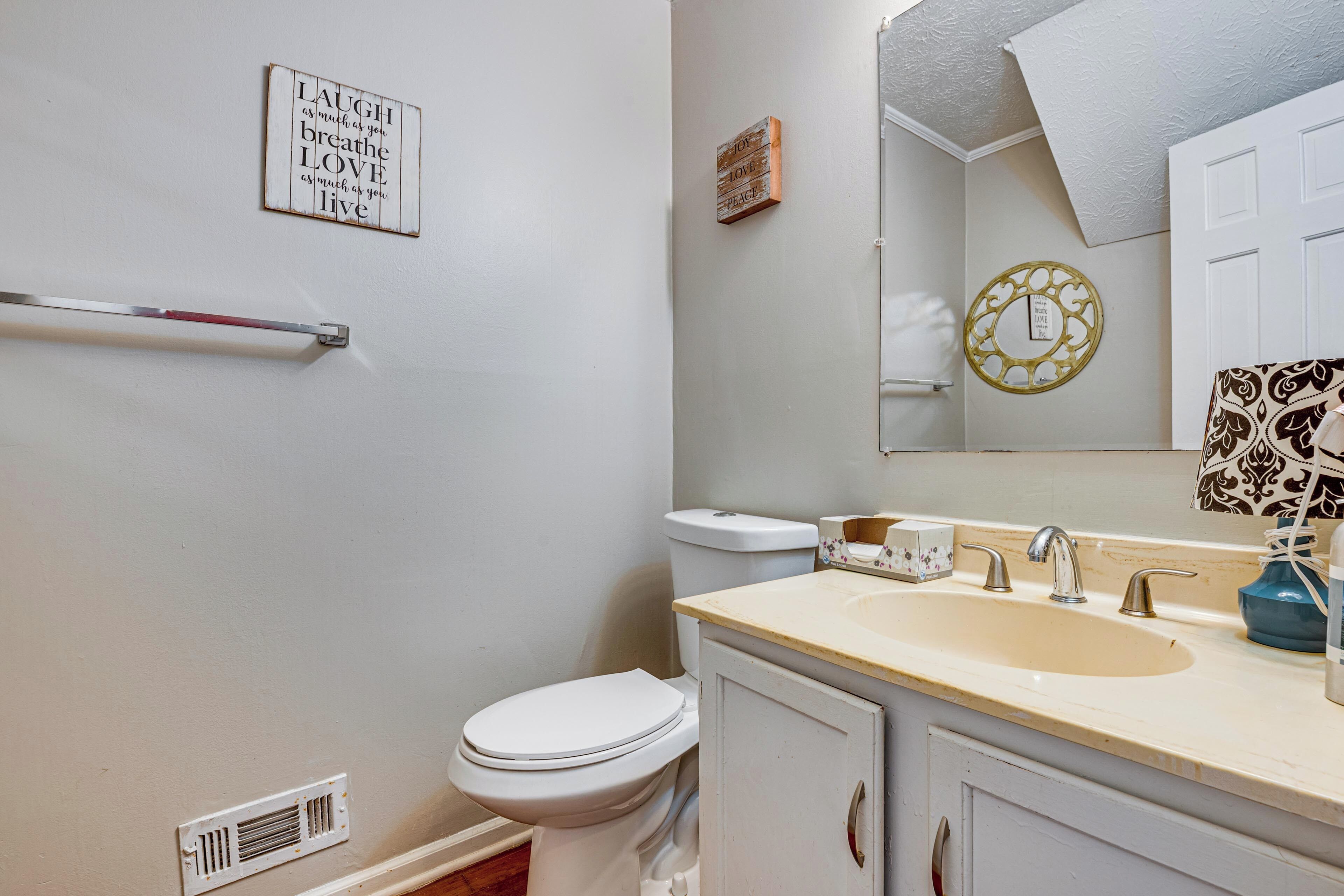 Une salle de bain équipée de toilettes, d’un lavabo, d’un miroir et d’un porte-serviettes.