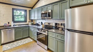 Uma cozinha moderna com armários verdes, eletrodomésticos de aço inoxidável e uma janela que oferece luz natural.