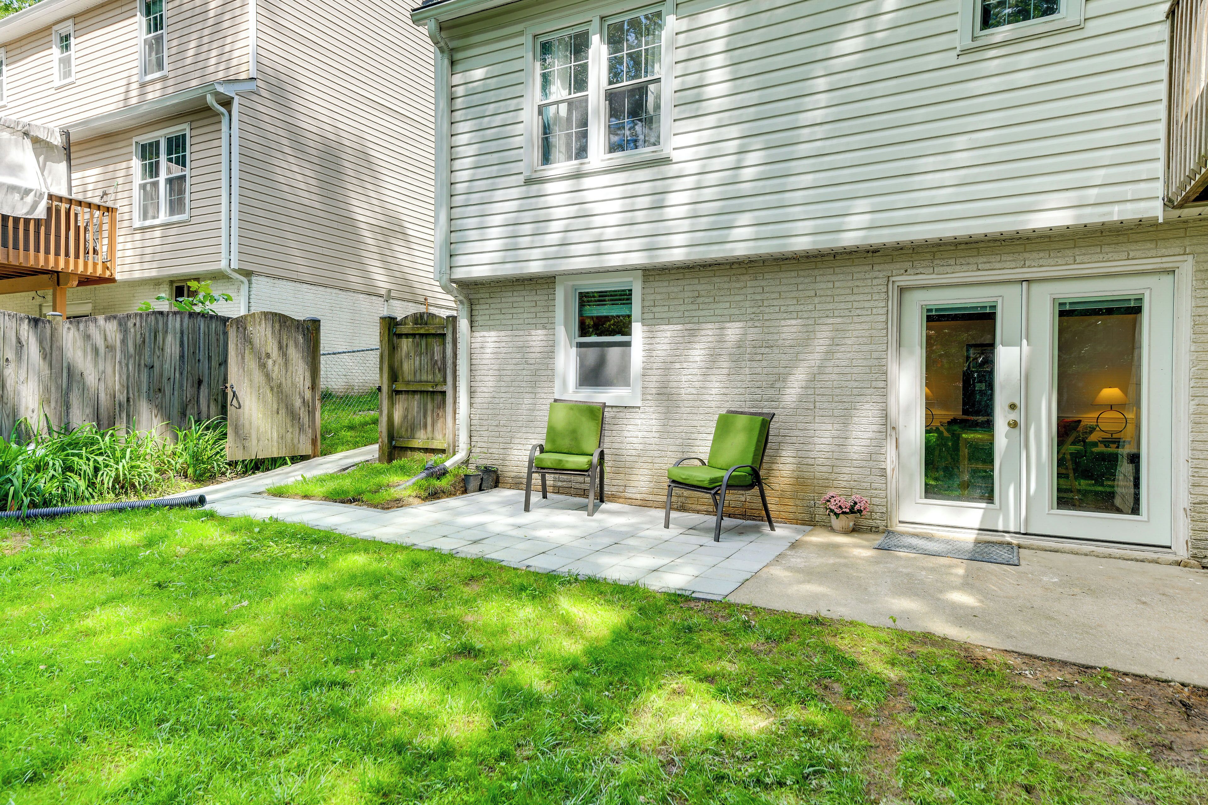 A house with a patio, two green chairs, a wooden fence, and a brick wall.