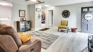 A living room with a brown leather sofa, a yellow armchair, a black clock, and a door with a 'Welcome' sign. - Walkable Location! Peaceful Toccoa Escape w/ Yard (Toccoa)