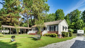 A single-story house with a front porch, a small lawn, and a gravel driveway. - Walkable Location! Peaceful Toccoa Escape w/ Yard (Toccoa)