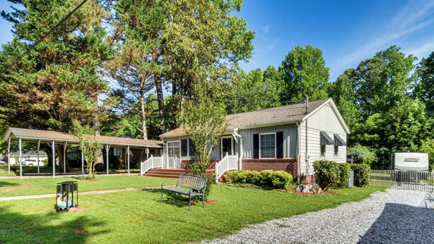 A single-story house with a front porch, a small lawn, and a gravel driveway. - Walkable Location! Peaceful Toccoa Escape w/ Yard (Toccoa)