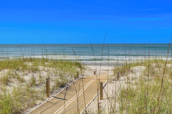 Ein Strandweg, der zum Meer führt, mit blauem Himmel.