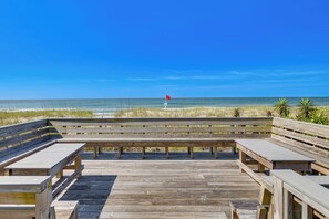 Ein hölzerner Steg führt zum Strand, mit einem roten Warnflagge.