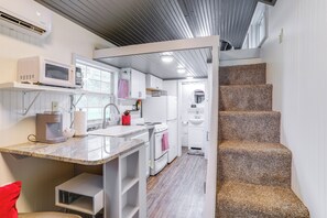 A compact kitchen with a microwave, stove, and sink, a small seating area, and a staircase leading to an upper level. - 2-studio Retreat on White River w/ Swimming Hole (Mountain View)