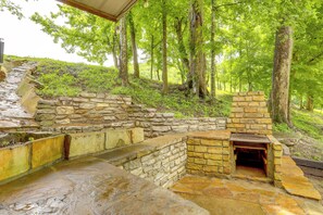 A stone-built outdoor fireplace area with steps leading up to it, surrounded by lush greenery and trees. - 2-studio Retreat on White River w/ Swimming Hole (Mountain View)