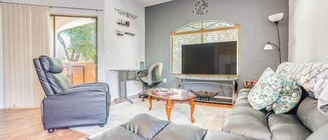 Ein modernes Wohnzimmer mit einer Ledersofa, einem Couchtisch, einem Fernseher und einem großen Fenster.