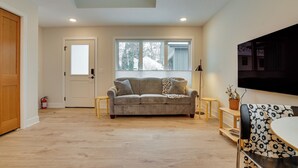 A living room with a grey sofa, a coffee table, and a TV mounted on the wall.