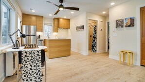 A modern kitchen with wooden cabinets, a stainless steel refrigerator, and a ceiling fan.