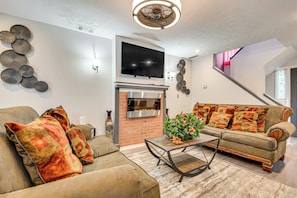 A living room with a fireplace, sofa, and television.