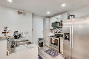 A modern kitchen with a stainless steel refrigerator, microwave, oven, and sink.