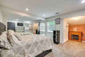 A bedroom with a bed, a fireplace, a mirror, and a closet.