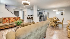 A living room with a sofa, a dining table with chairs, a kitchen area with appliances, and a staircase. - 3BR Townhome Near Downtown Decatur (Decatur)
