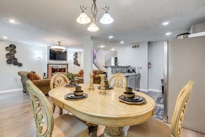 A dining area with a wooden table, chairs, and a chandelier.