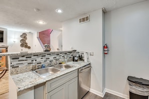 A kitchen with a granite countertop, stainless steel sink, and a dishwasher.