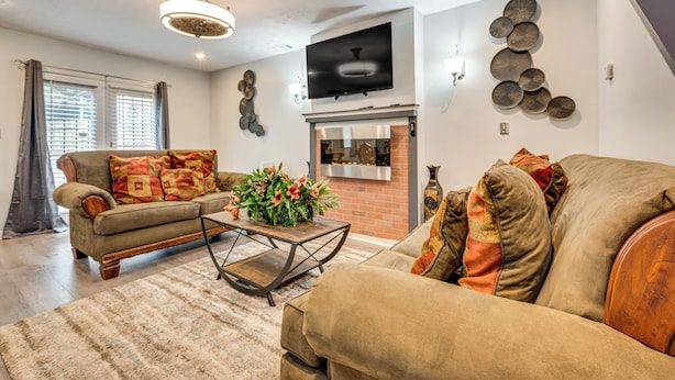 A living room with a sofa, a coffee table, a fireplace, and a television mounted on the wall. - 3BR Townhome Near Downtown Decatur (Decatur)