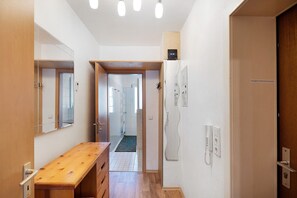A hallway with a wooden bench, a door with a phone, and a wall-mounted light fixture. - Apartment 'Möblierte Übernachtungen' with Wi-Fi (Essen)