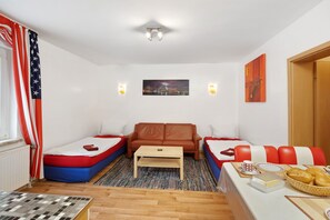 A room with a bed, a sofa, a coffee table, a dining table with bread, and a painting on the wall. - Apartment 'Möblierte Übernachtungen' with Wi-Fi (Essen)