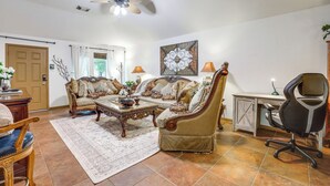 Uma sala de estar com sofá, mesa de centro e escrivaninha com cadeira.
