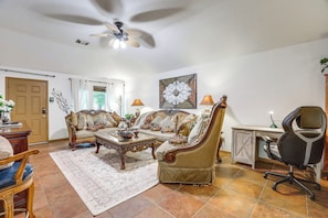 A living room with a sofa, coffee table, and a desk with a chair. - 4 Mi to Lake Houston! Single-level Home w/ Yard (Humble)