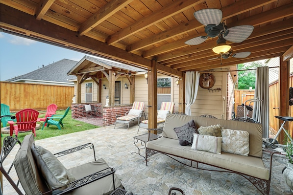 An outdoor patio with a wooden ceiling, stone flooring, a sofa with cushions, and a dining area with chairs. - 4 Mi to Lake Houston! Single-level Home w/ Yard (Humble)
