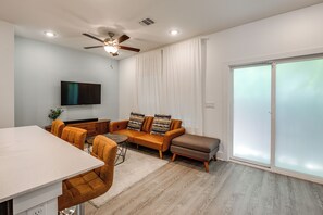 Ein modernes Wohnzimmer mit Sofa, Hocker und Essbereich.