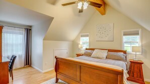 Een slaapkamer met een houten bed, een plafondventilator, een raam met zonwering en een deur.